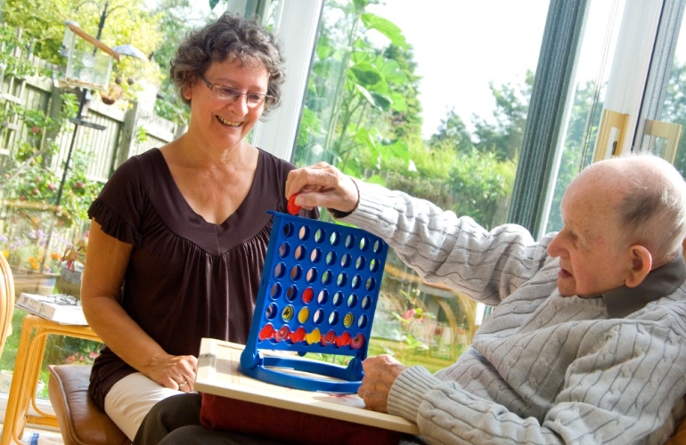 Female carer playing connect 4 with male