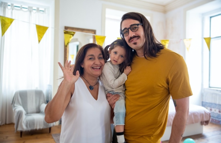 Family carrying a baby in a house waving