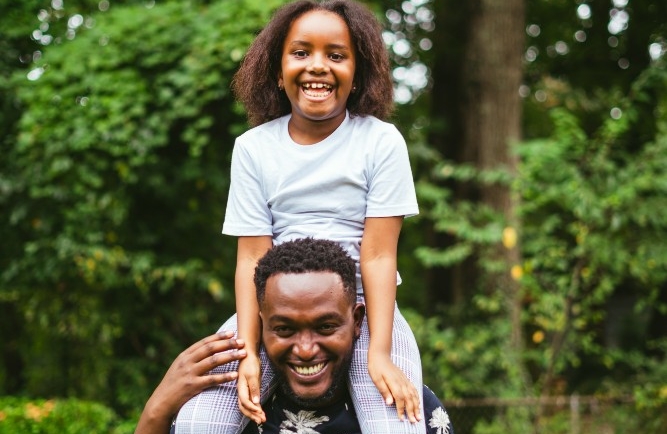 Daughter on fathers shoulders both smiling