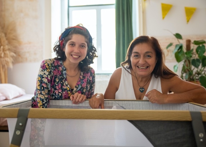 Smiling over a cot with a baby inside