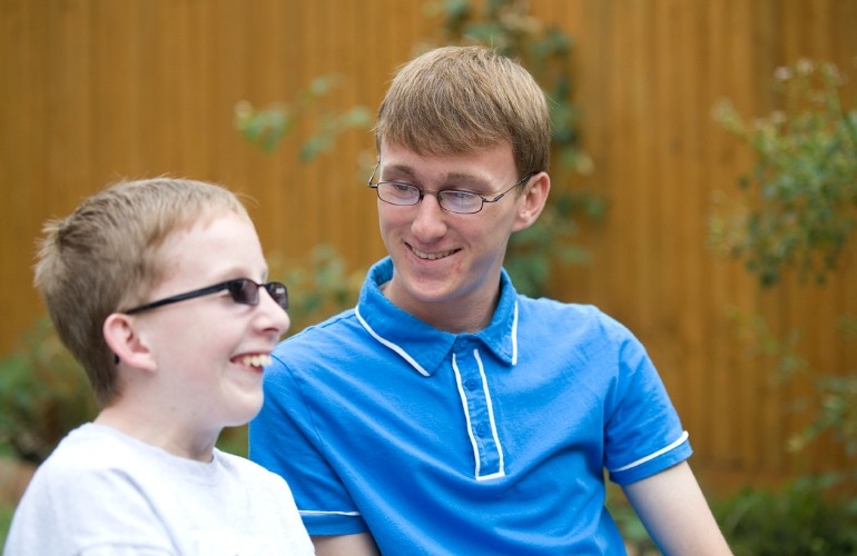 Young carer looking at his younger brother outside