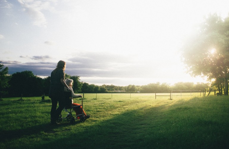 Lady in a wheelchair being pushed in a field