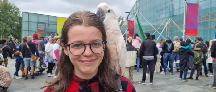 Kirsty, young carer, with parrot on shoulder next to Manchester Football Museum