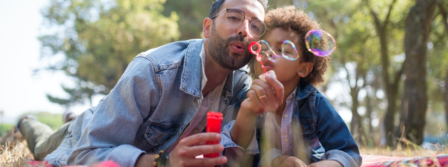 Father and son lying down blowing bubbles