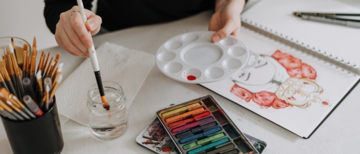 Person mixing watercolour and using pastel creating a beautiful drawing of girl with flowers in her hair