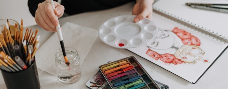 Person mixing watercolour and using pastel creating a beautiful drawing of girl with flowers in her hair