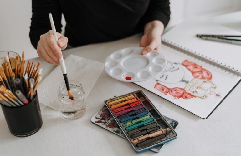 Person mixing watercolour and using pastel creating a beautiful drawing of girl with flowers in her hair