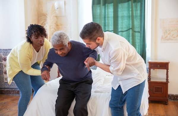 Two nurses helping an elderly man